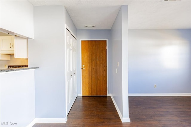 corridor with visible vents, baseboards, and wood finished floors