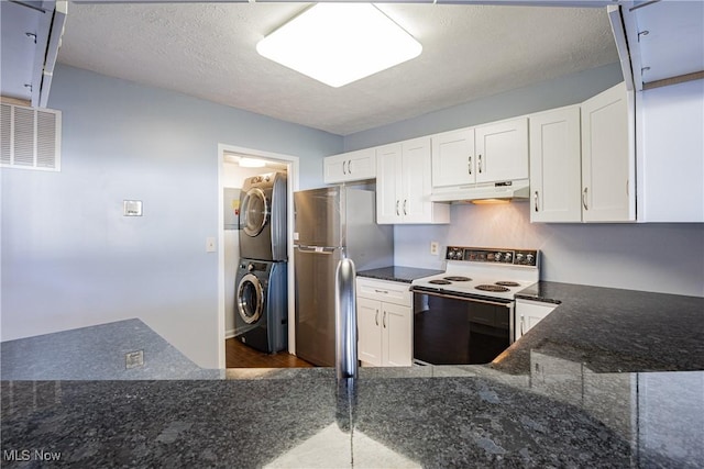 kitchen with under cabinet range hood, dark stone counters, stacked washer and clothes dryer, range with electric stovetop, and freestanding refrigerator