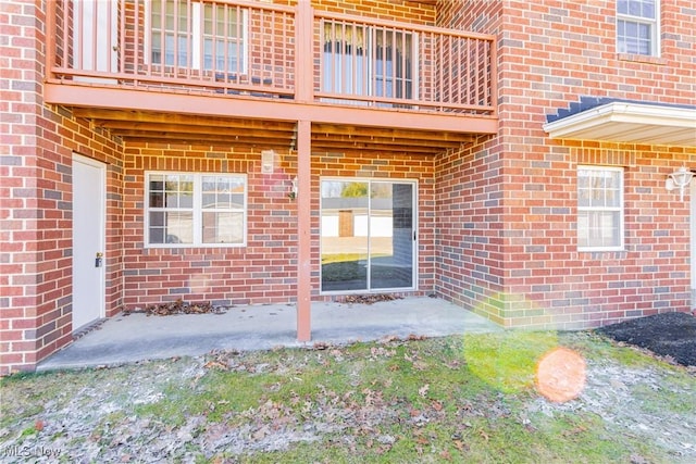 doorway to property with a balcony and brick siding