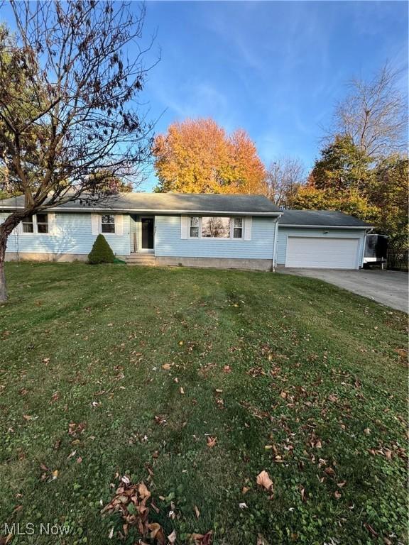 view of front of home featuring concrete driveway, a garage, and a front yard