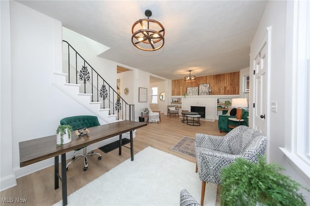 office space with baseboards, an inviting chandelier, light wood-style flooring, and a fireplace