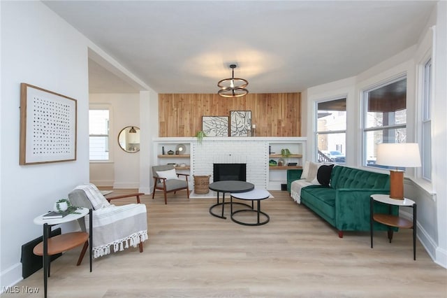 living area featuring a brick fireplace, wooden walls, wood finished floors, and baseboards