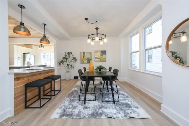 dining area with baseboards, light wood-style floors, and an inviting chandelier