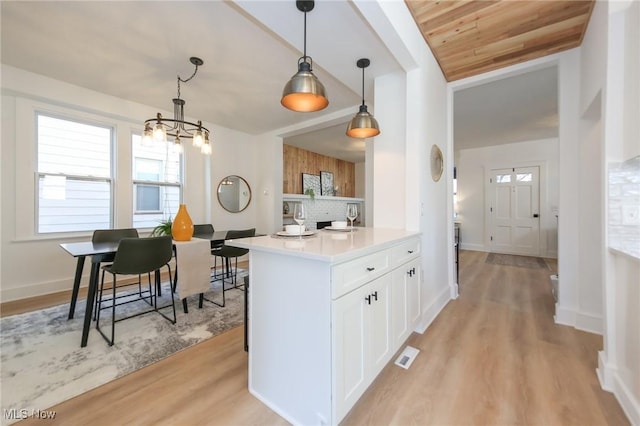 kitchen with visible vents, hanging light fixtures, light wood-style floors, white cabinetry, and a chandelier