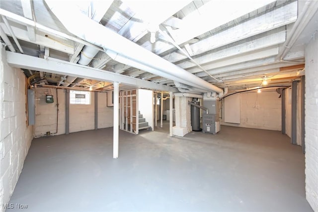 below grade area featuring electric panel, heating unit, and stairs