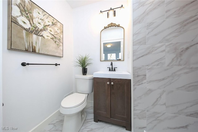 bathroom with vanity, toilet, baseboards, and marble finish floor