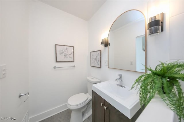 bathroom with toilet, vanity, and baseboards