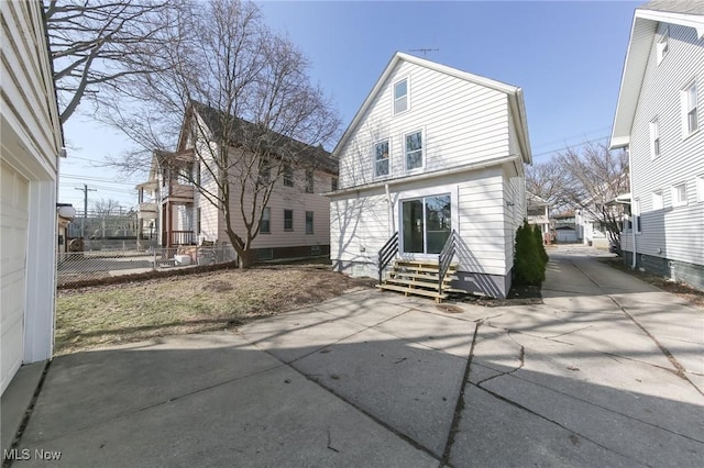 rear view of property featuring fence and entry steps