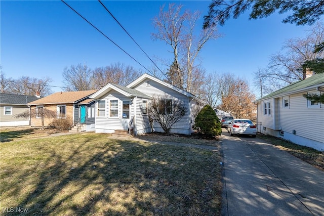 view of front of property with entry steps, a front lawn, and driveway