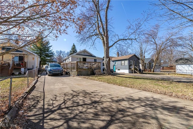 view of front of property featuring a deck, a front lawn, driveway, fence, and a residential view