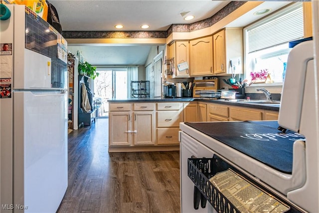 kitchen with dark countertops, dark wood-type flooring, light brown cabinetry, a peninsula, and freestanding refrigerator