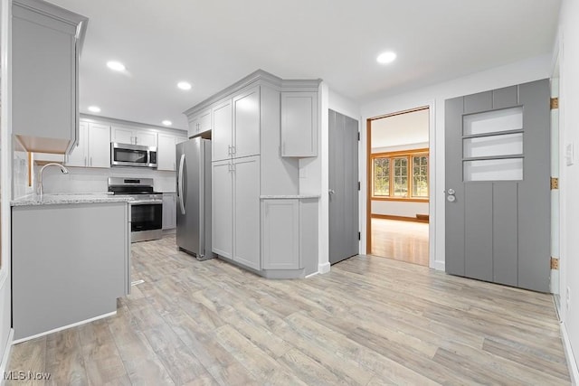 kitchen featuring gray cabinetry, recessed lighting, light wood-style flooring, stainless steel appliances, and a sink