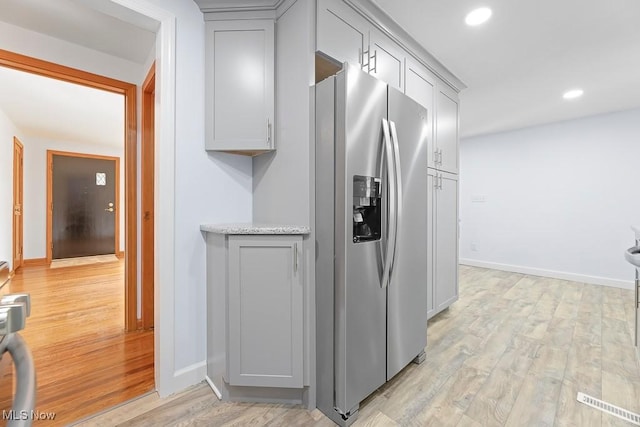 kitchen with baseboards, recessed lighting, gray cabinets, light wood-style floors, and stainless steel fridge