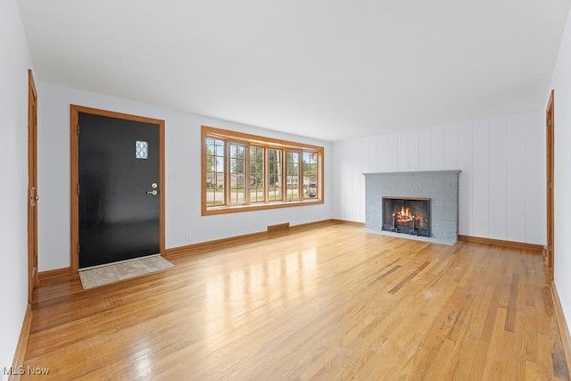 unfurnished living room featuring visible vents, a brick fireplace, light wood-type flooring, and baseboards