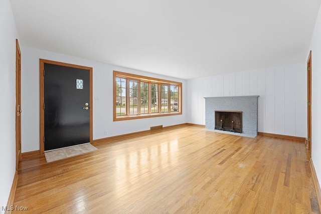 unfurnished living room with visible vents, baseboards, a fireplace, and light wood finished floors