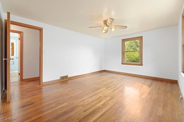 spare room with baseboards, wood finished floors, visible vents, and ceiling fan