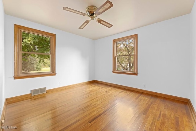 unfurnished room with visible vents, baseboards, ceiling fan, and wood finished floors