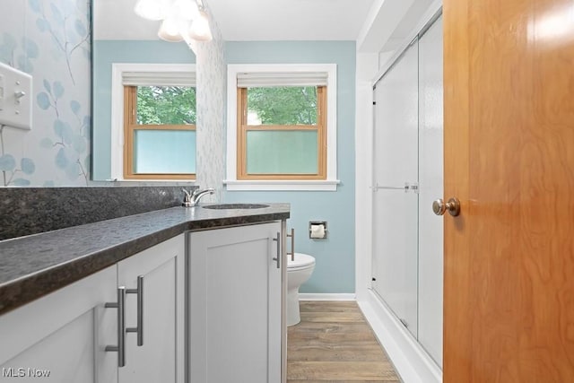 full bathroom with vanity, wood finished floors, baseboards, a stall shower, and toilet