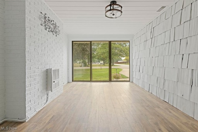 interior space featuring visible vents, heating unit, wood finished floors, and brick wall