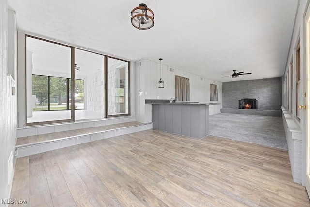 interior space with a ceiling fan, a fireplace, and light wood-type flooring