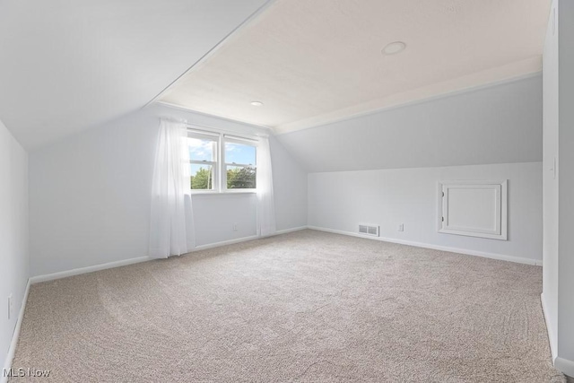 additional living space featuring visible vents, carpet floors, baseboards, and vaulted ceiling