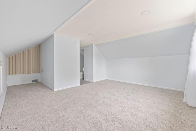 additional living space with visible vents, baseboards, lofted ceiling, and carpet floors