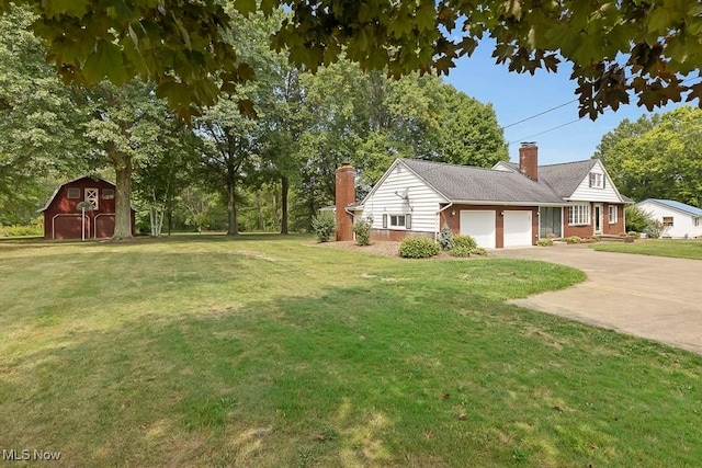 view of yard featuring a barn, an outdoor structure, an attached garage, and driveway