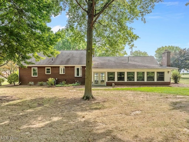 ranch-style house featuring french doors, brick siding, roof with shingles, and a chimney