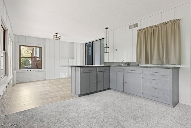 kitchen featuring a peninsula, visible vents, gray cabinets, and a sink