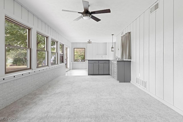 unfurnished sunroom with visible vents and a ceiling fan