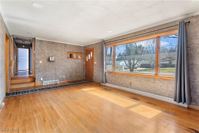 spare room with visible vents, a healthy amount of sunlight, and wood finished floors