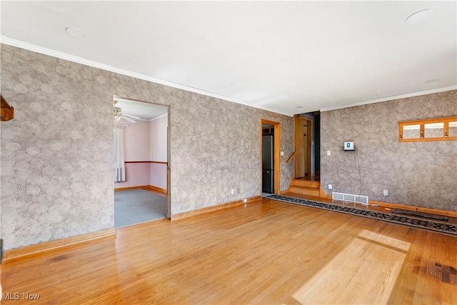 unfurnished living room featuring ceiling fan, visible vents, wood finished floors, and crown molding