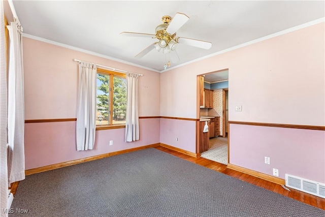 empty room with visible vents, baseboards, ornamental molding, wood finished floors, and a ceiling fan