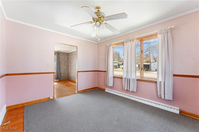 spare room featuring ornamental molding, baseboards, a ceiling fan, and a baseboard radiator