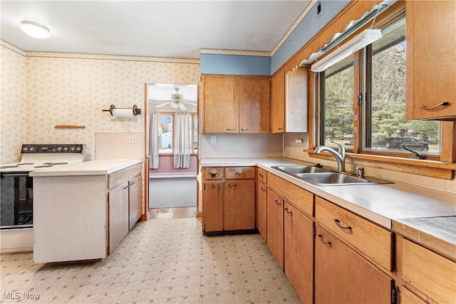 kitchen featuring wallpapered walls, light countertops, electric range, and a sink