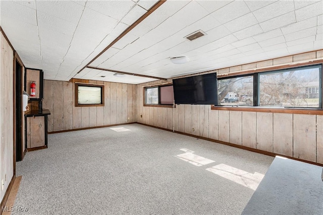 below grade area with visible vents, baseboards, wooden walls, and carpet flooring