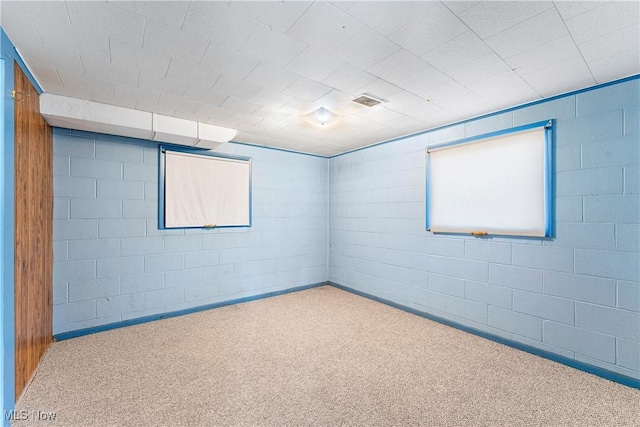 carpeted spare room featuring concrete block wall