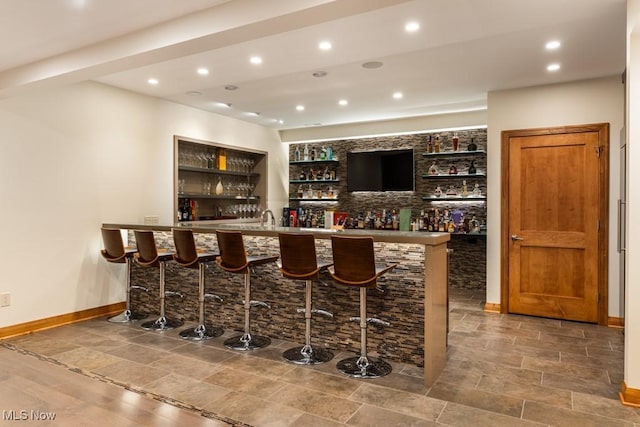 bar with recessed lighting, indoor wet bar, and baseboards