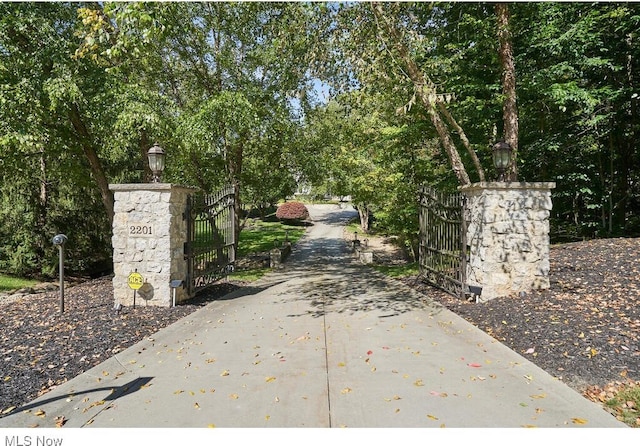 view of home's community with concrete driveway and a gate