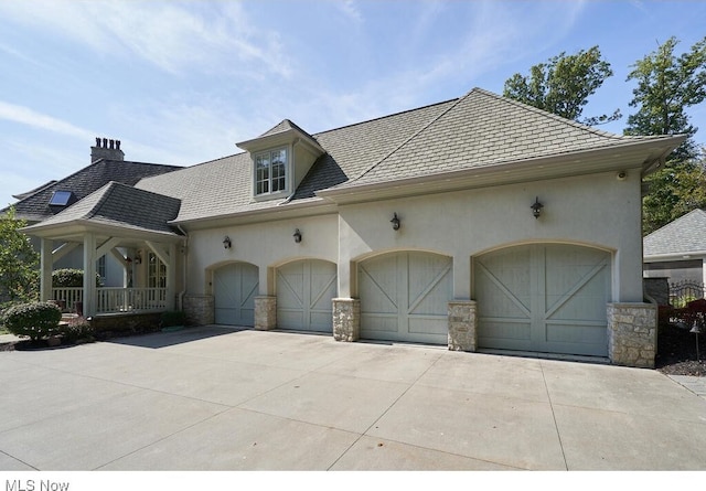 view of front of house with concrete driveway, an attached garage, a chimney, and stucco siding