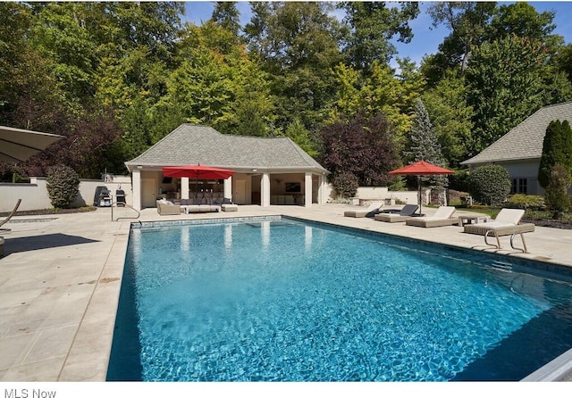 outdoor pool with fence, an outdoor structure, a storage structure, outdoor lounge area, and a patio area