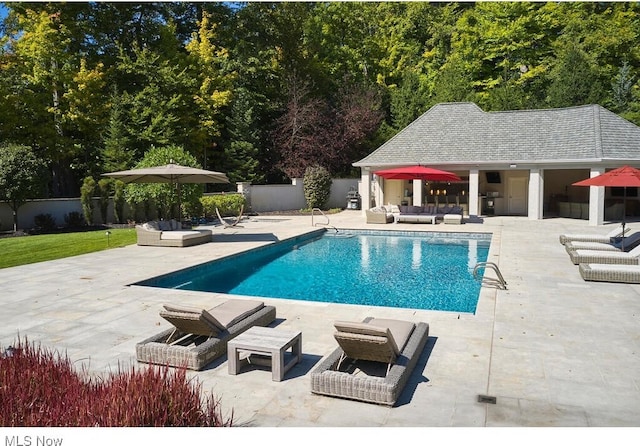 view of pool with fence, a storage structure, a patio area, an outdoor hangout area, and an outbuilding