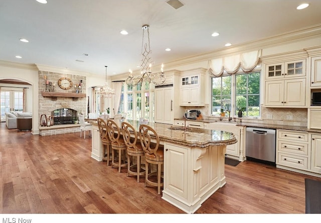 kitchen featuring a breakfast bar, an island with sink, a fireplace, dishwasher, and tasteful backsplash