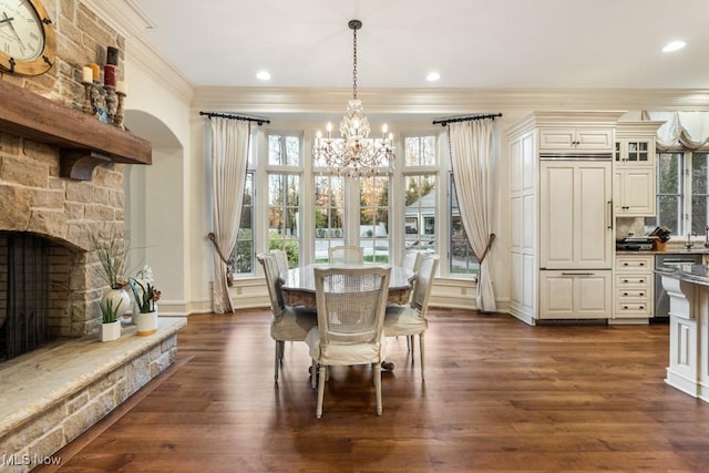 dining area with an inviting chandelier, ornamental molding, dark wood-style flooring, and a healthy amount of sunlight