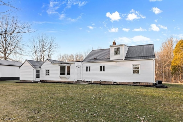 back of property with a lawn, a chimney, and metal roof