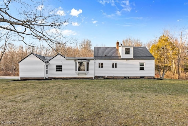 back of property featuring metal roof, a lawn, and a chimney