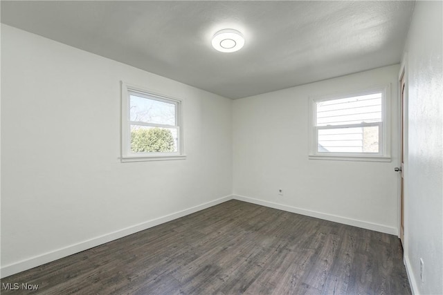 unfurnished room featuring dark wood finished floors, baseboards, and a wealth of natural light