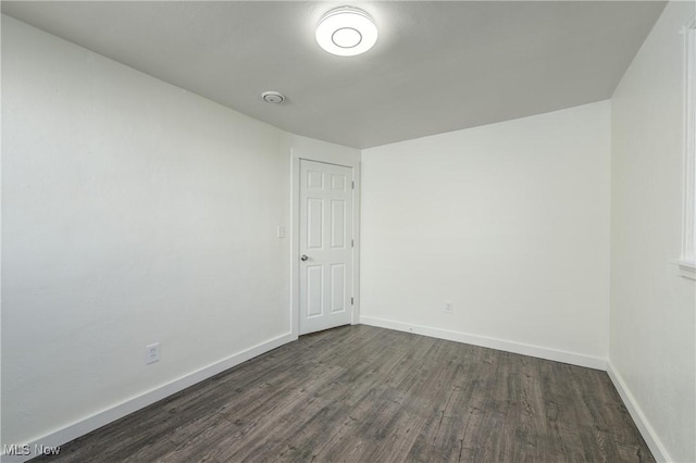 empty room with baseboards and dark wood-type flooring