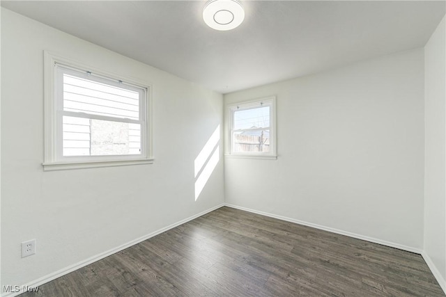 empty room featuring baseboards and dark wood-style flooring