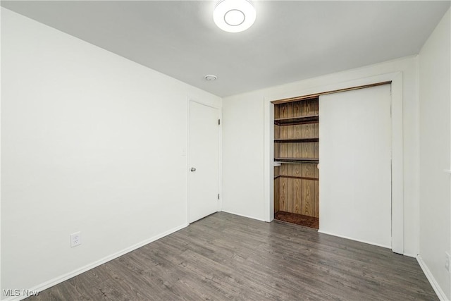 unfurnished bedroom with a closet, baseboards, and wood finished floors